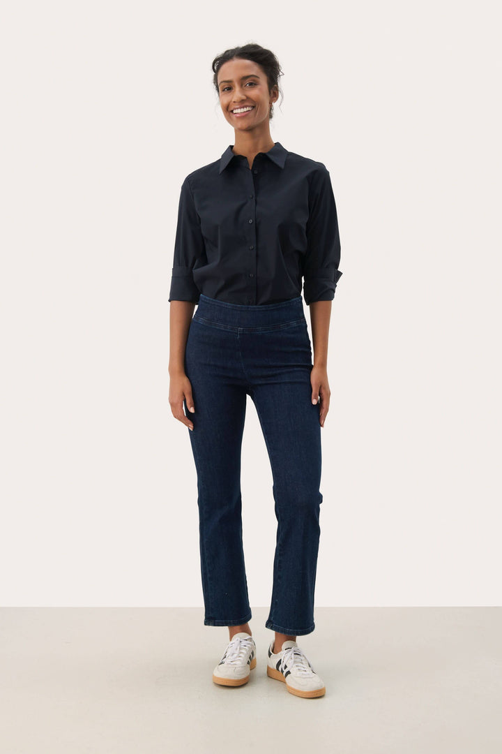 Modèle portant le Pantalon Nikela taille haute avec coupe évasée et tissu extensible pour une allure moderne et confortable.