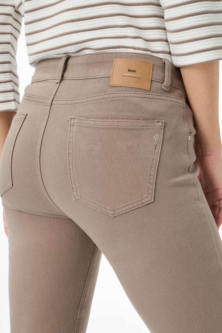Vue latérale d'un Pantalon Shakira ajusté, taille mi-haute, couleur taupe, porté avec un haut rayé, montrant la coupe slim fit élégante.