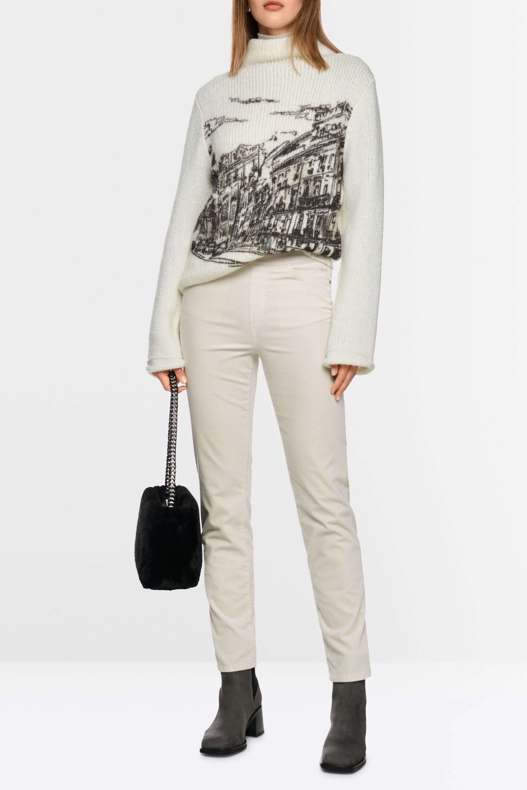 Femme portant le pantalon Siena à taille élastique en coton extensible beige, avec un pull imprimé et bottines noires.