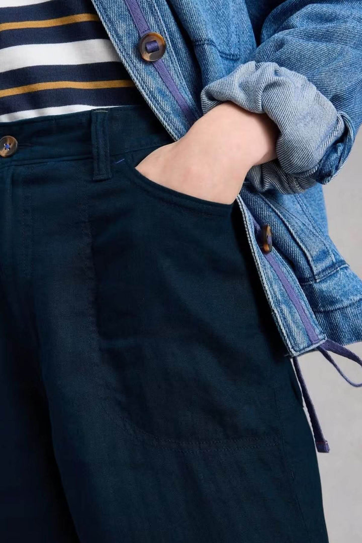 Person wearing Pantalon Tia à jambes larges with pocket detail and casual outfit including denim jacket.