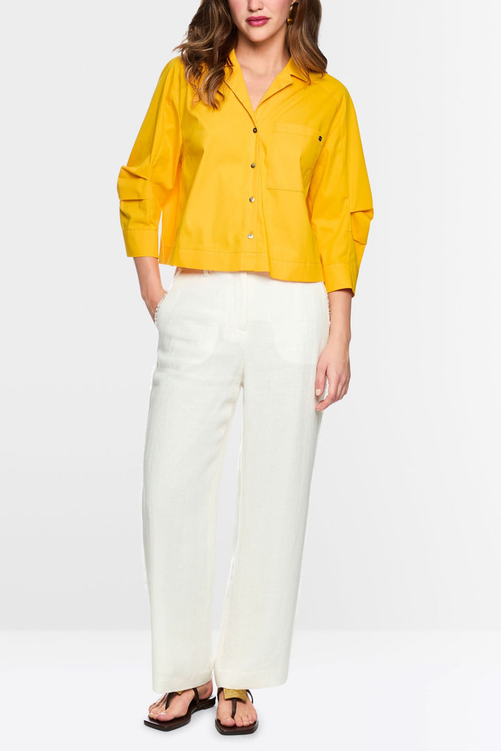 Femme portant le Pantalon WUKARI large texturé blanc avec une chemise jaune, montrant un style fluide et élégant.