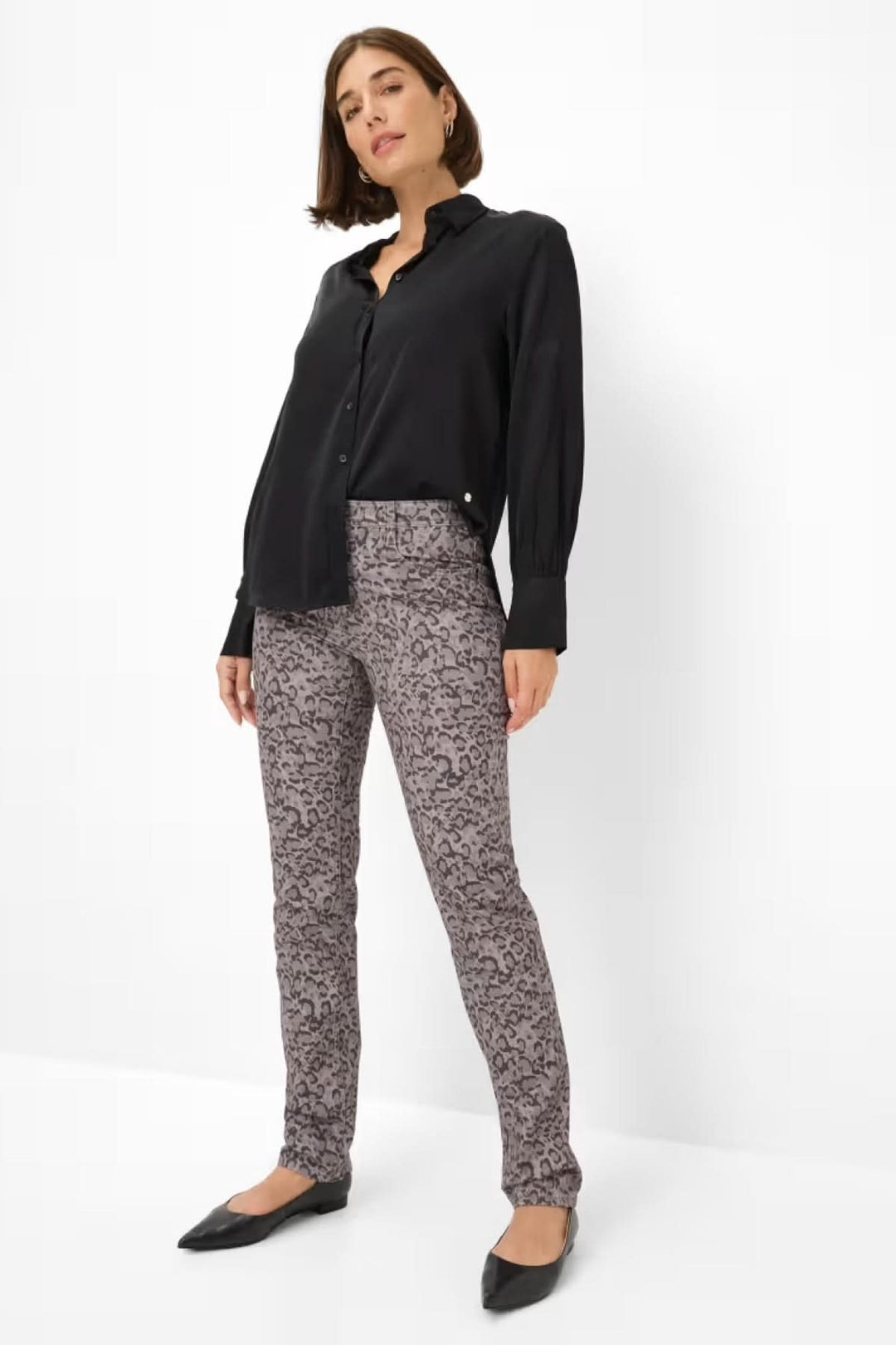Femme portant un pantalon ajusté à imprimé graphique avec chemise noire, montrant style élégant et moderne.
