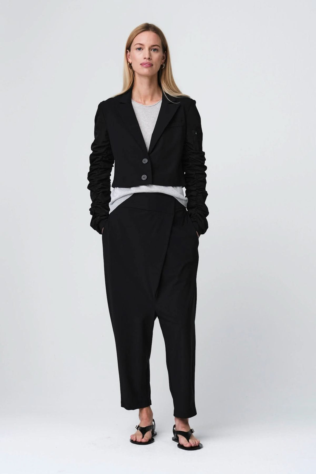 Modèle portant un pantalon ample à taille structurée, coupe fluide, moderne et élégante. Pantalon noir avec poches latérales discrètes.