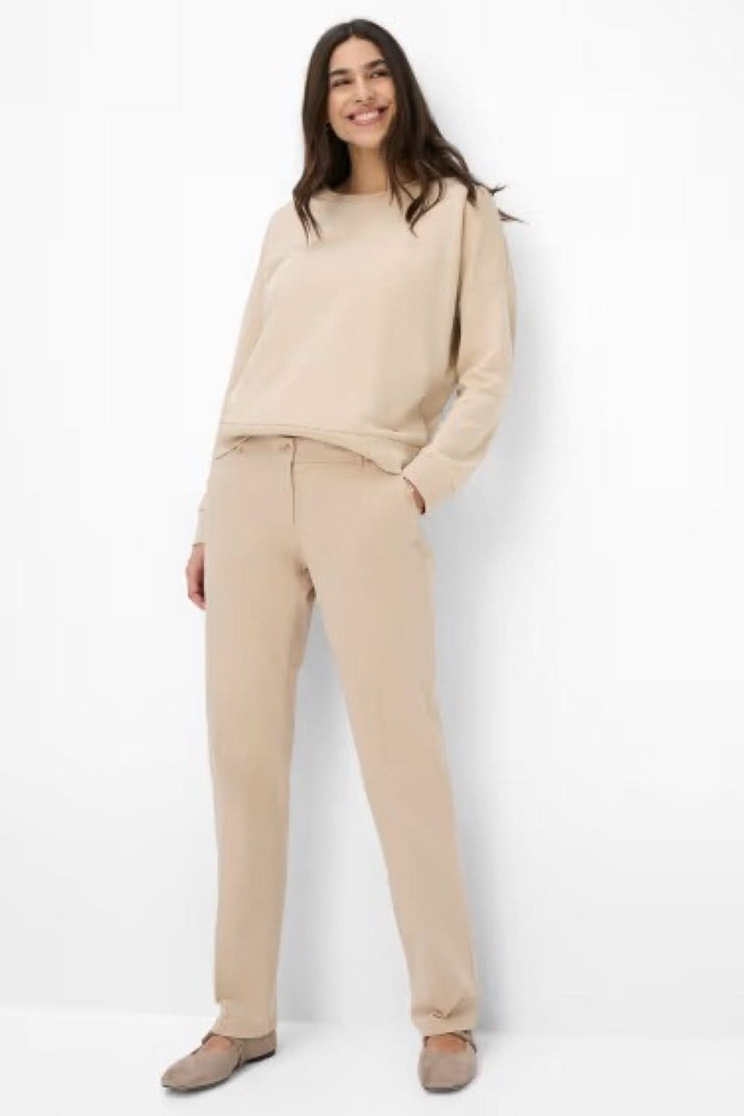 Femme souriante portant un pantalon chino Maron beige, associé à un haut décontracté et des chaussures confortables.