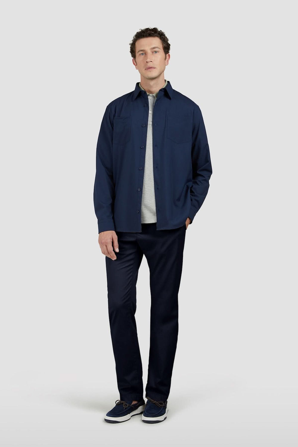 Homme portant un pantalon chino en coton et soie extensible avec chemise bleue, montrant élégance et confort pour un style polyvalent.