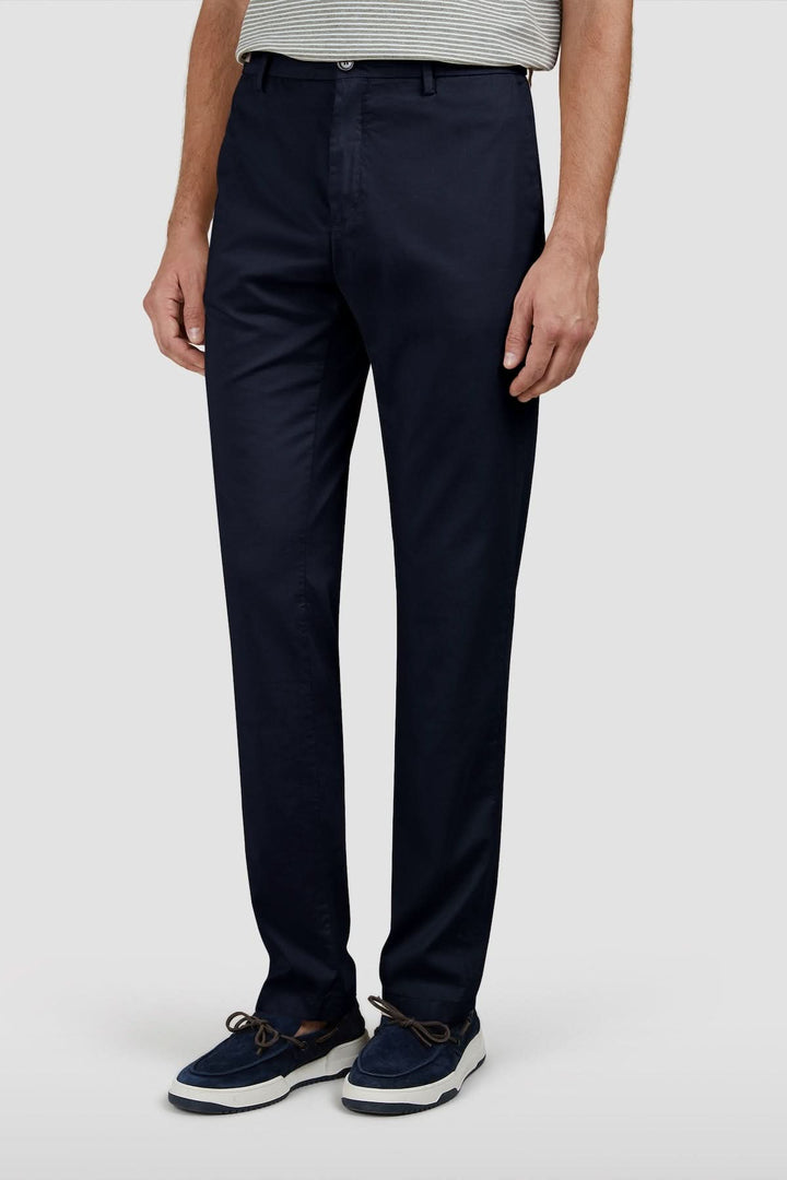 Homme portant un pantalon chino en coton et soie extensible, style élégant et polyvalent, coupe régulière, couleur sombre.