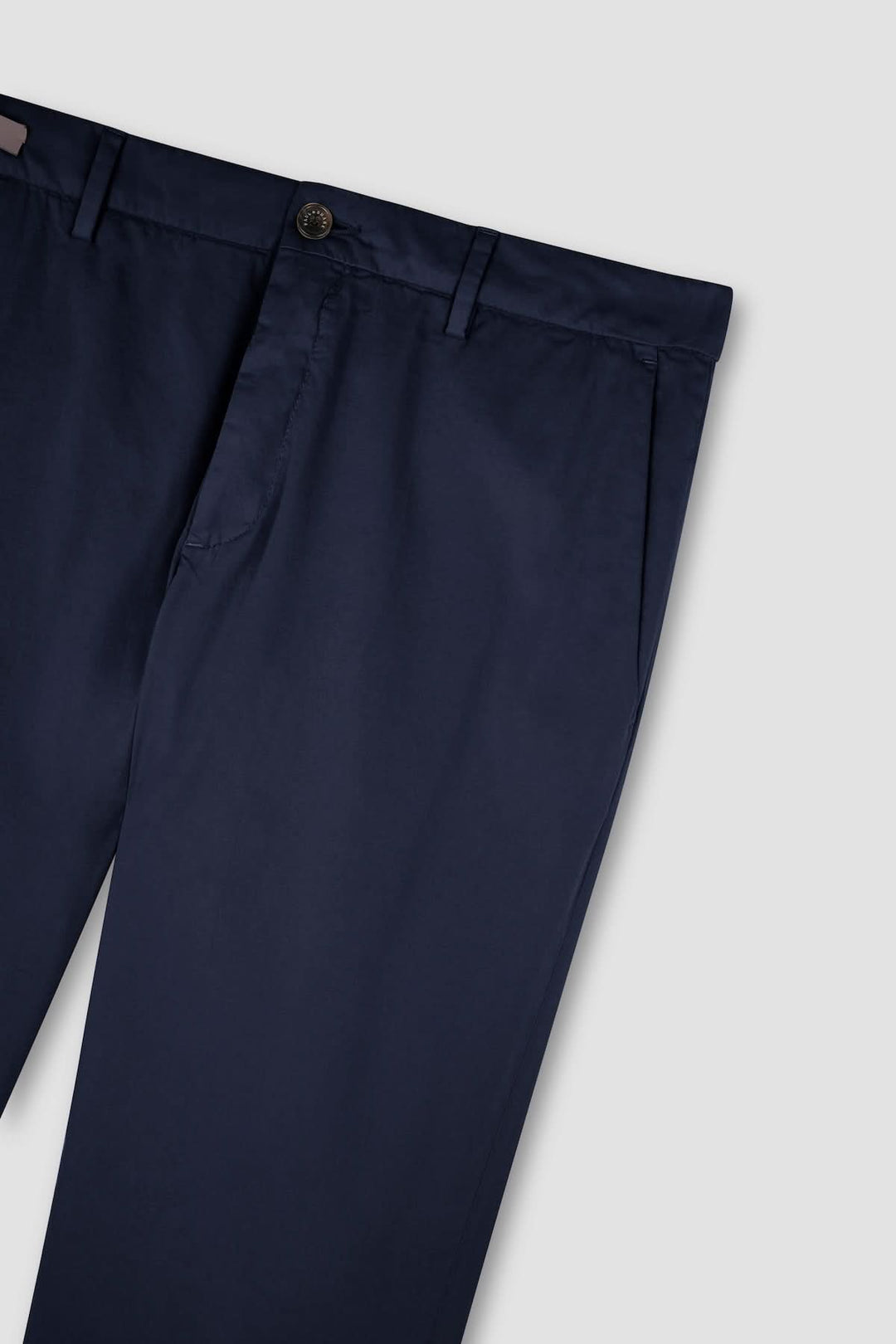 Pantalon chino en coton et soie extensible bleu marine sur fond gris, accent sur la qualité du tissu et la coupe élégante.