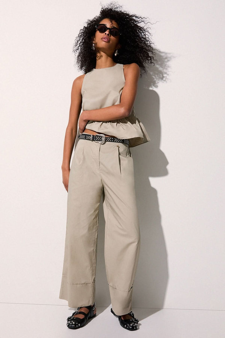Femme portant un pantalon chino à jambe large beige avec un top élégant, idéal pour un look décontracté ou habillé.