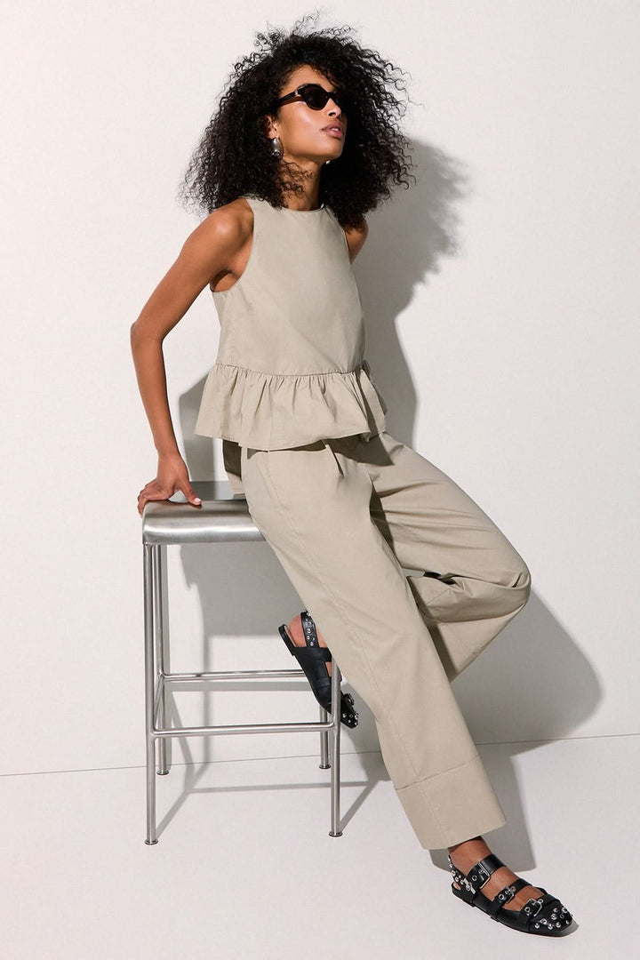 Femme portant un pantalon chino à jambe large beige avec un haut assorti, mode décontractée et élégante, style moderne.
