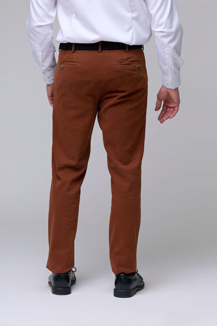Homme portant un pantalon chino moderne couleur marron, coupe droite avec tissu extensible et poches fonctionnelles, vue arrière.