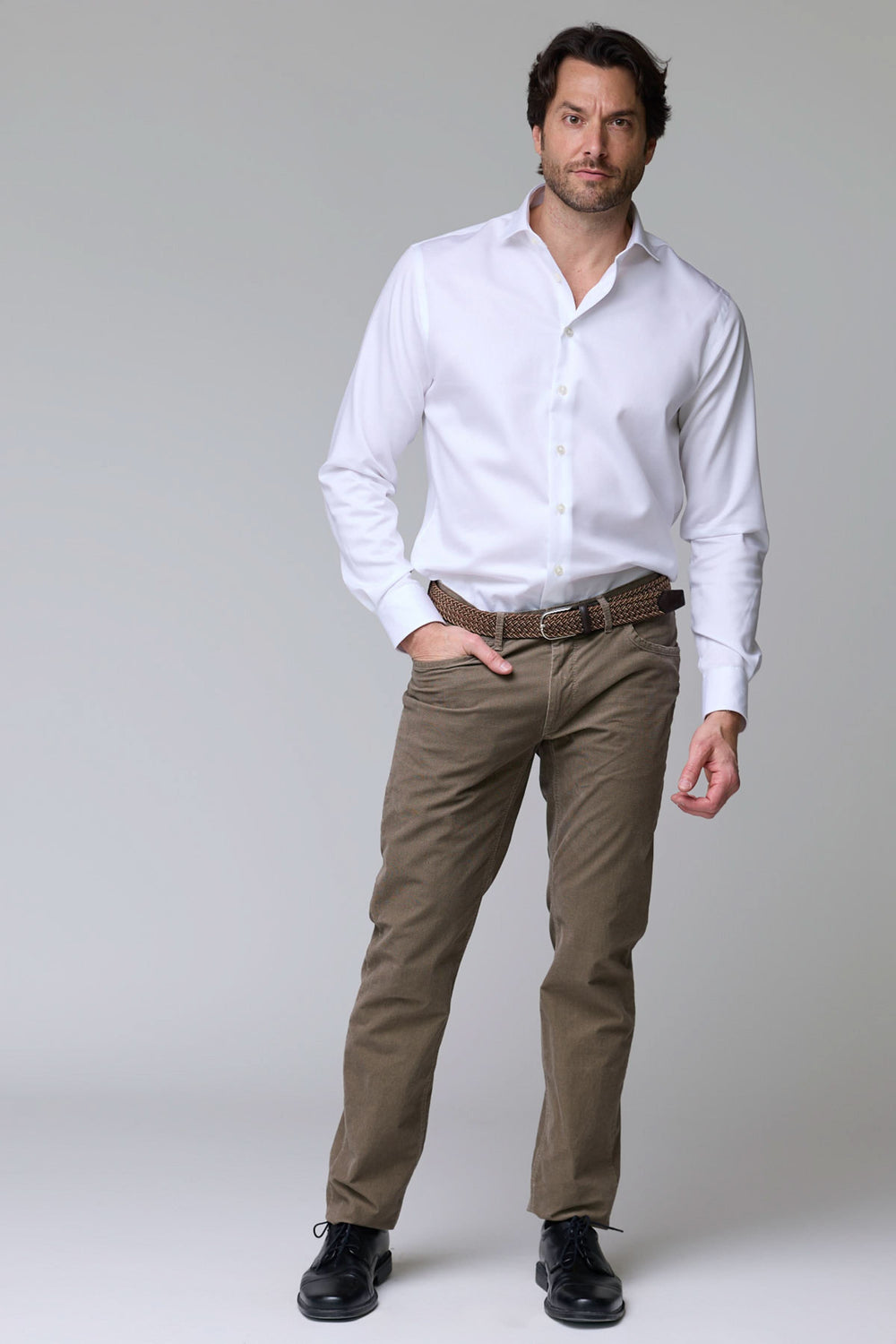 Homme portant un pantalon cinq poches en velours côtelé avec chemise blanche, alliant élégance et confort pour un style polyvalent.