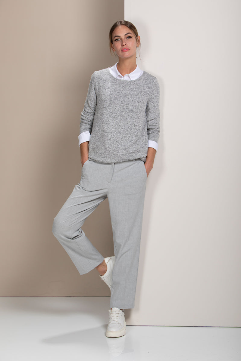 Femme portant un pantalon coupe droite gris avec chandail léger et baskets blanches, style bureau et quotidien.