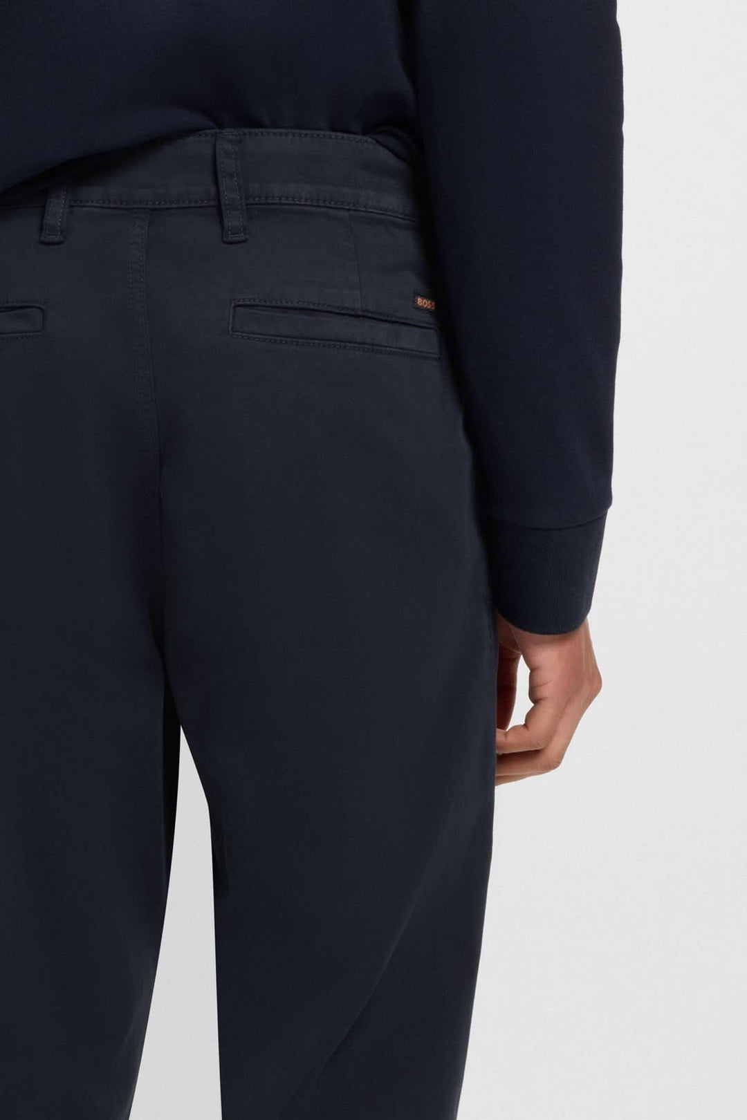 Dos du pantalon coupe fuselée en coton stretch, avec détails de poches et passants pour ceinture.