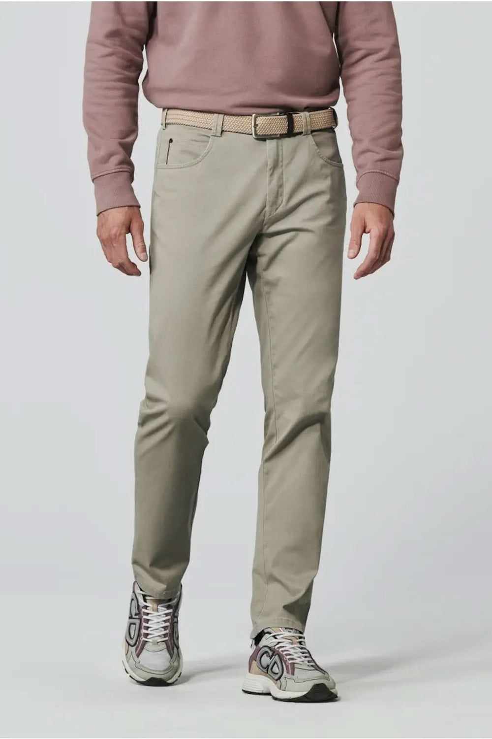 Pantalon décontracté beige avec coupe ajustée, porté avec un pull rose et des chaussures de sport.