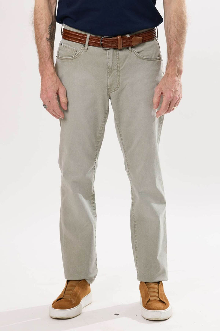 Pantalon droit en tissu souple, teinte légèrement délavée, porté avec un polo et une ceinture en cuir.