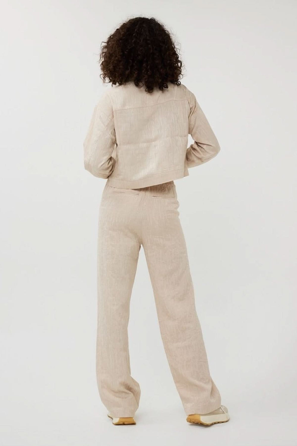 Femme vue de dos portant un pantalon ample en jacquard texturé et une veste assortie, style décontracté et moderne.