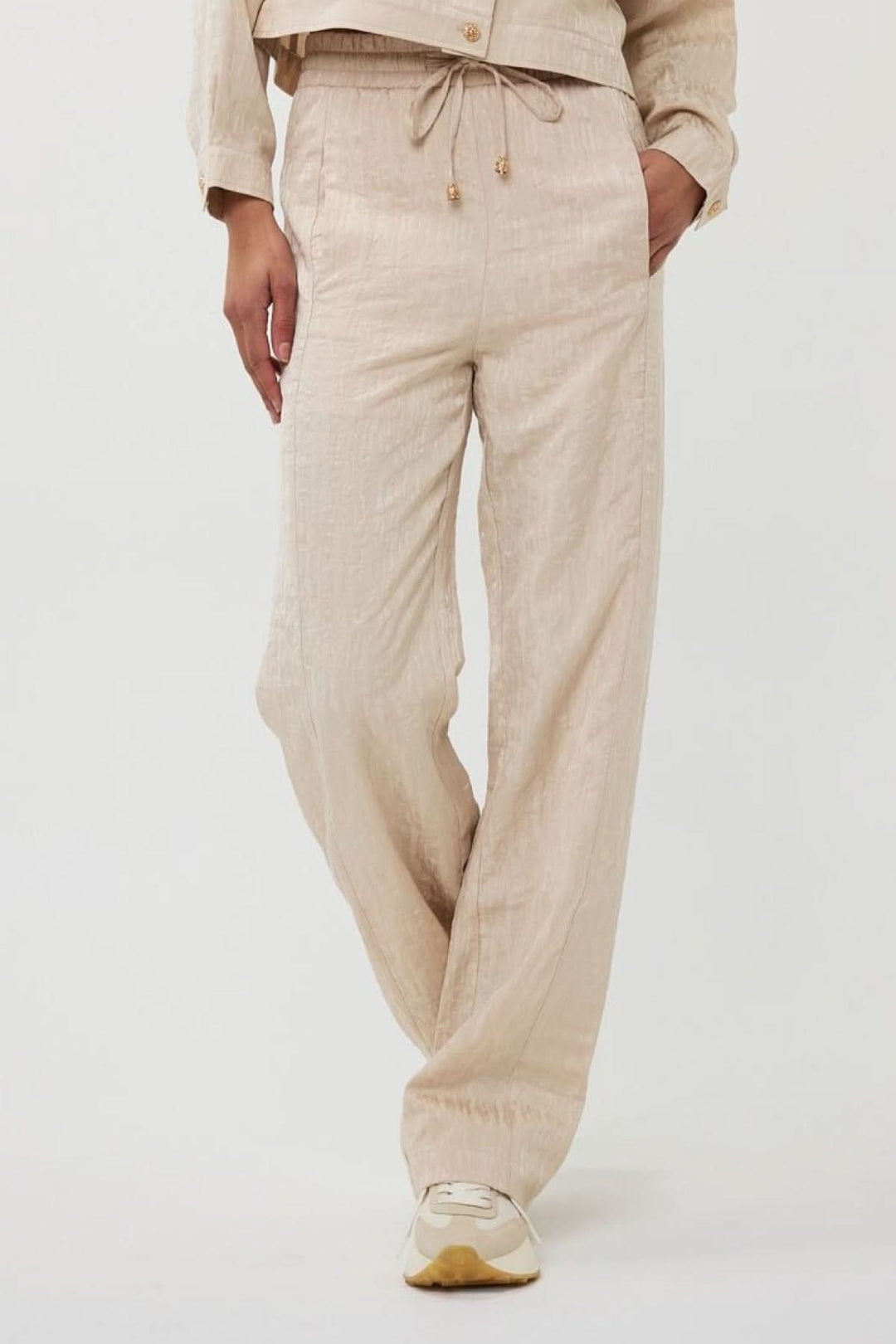 Pantalon ample en jacquard texturé beige avec taille élastique et cordon, idéal pour l'été.