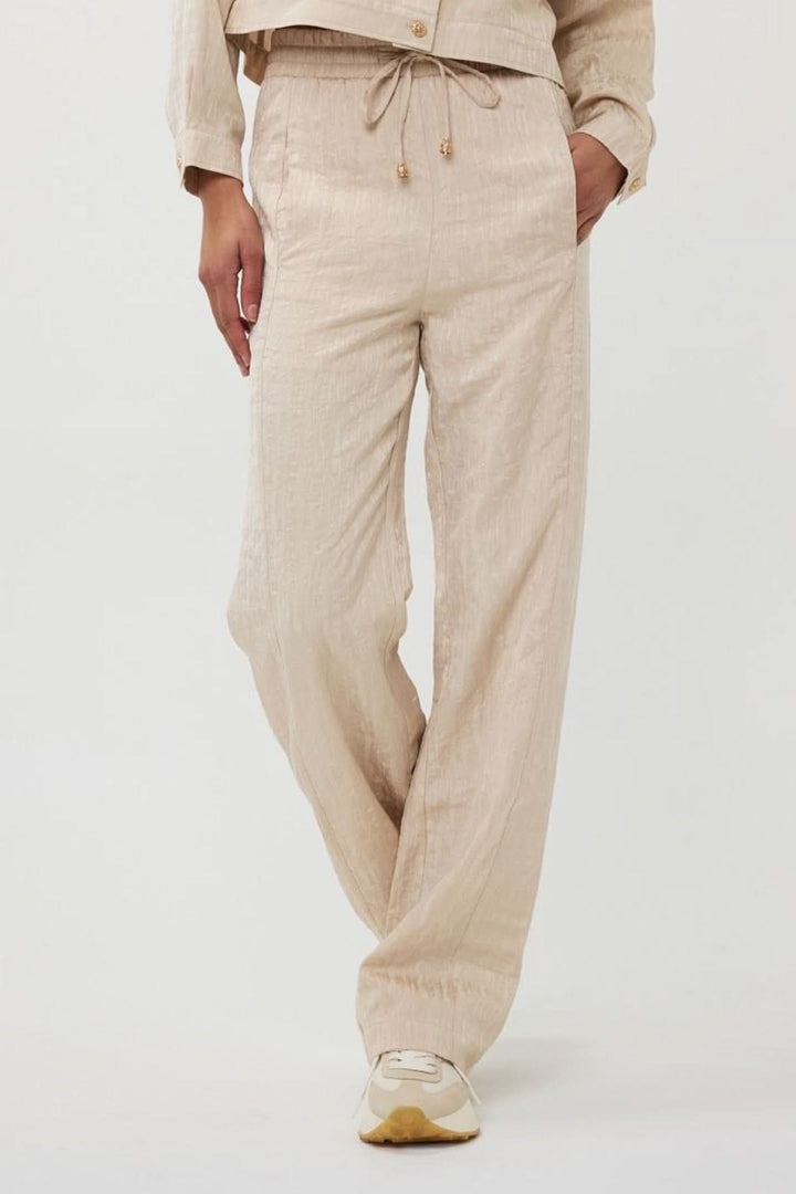 Pantalon ample en jacquard texturé beige avec taille élastique et cordon, idéal pour l'été.