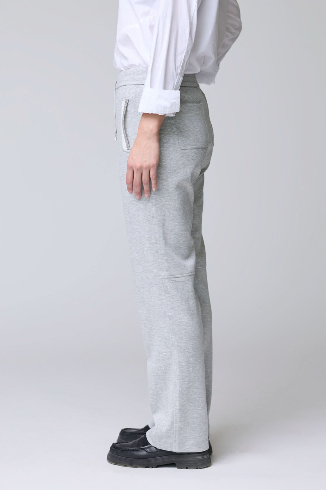 Homme portant un pantalon en jersey ajustable gris avec poches et cordon, offrant confort et style décontracté pour les sorties et détente.