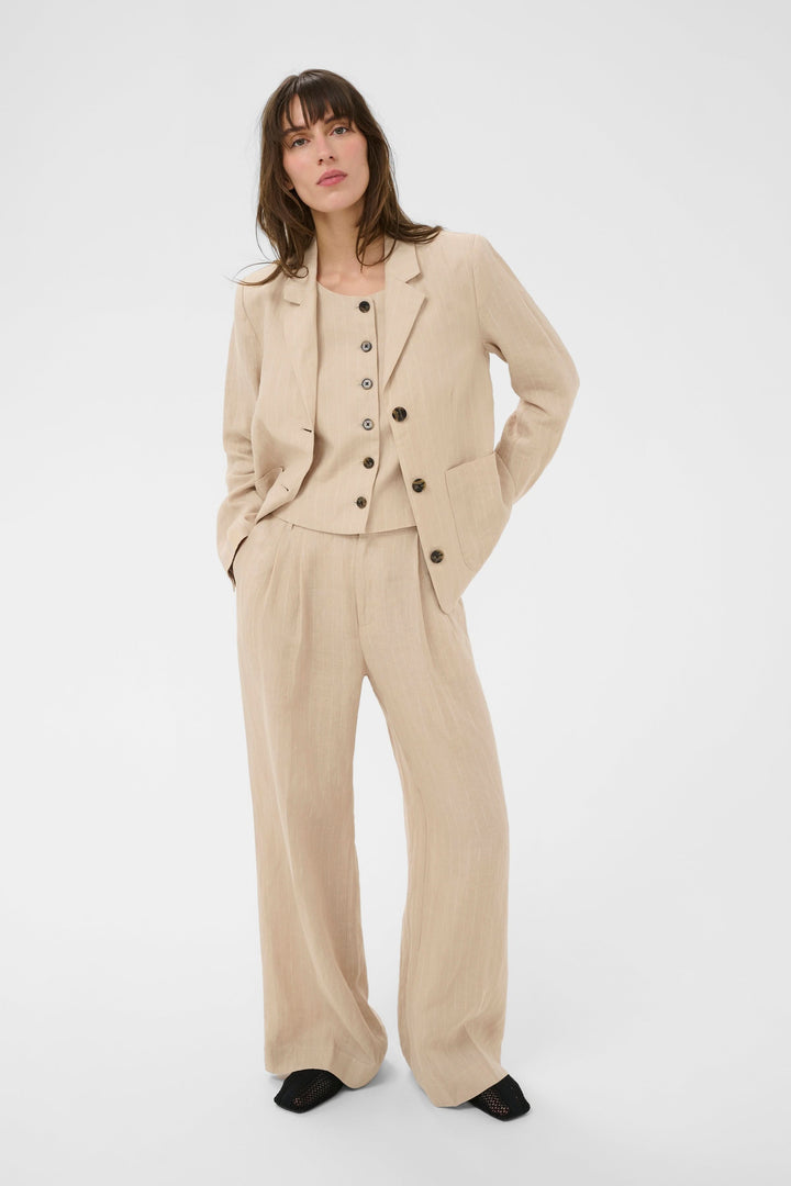 Femme portant un ensemble élégant incluant le Pantalon en lin Aliya, coupe droite et plis à l&