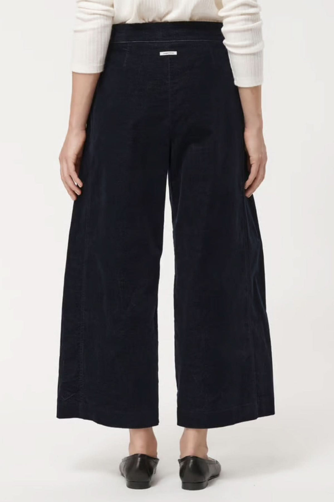 Pantalon en velours côtelé noir ample et raccourci, dos d'une femme, parfait pour l'automne et hiver, style et confort élégants.