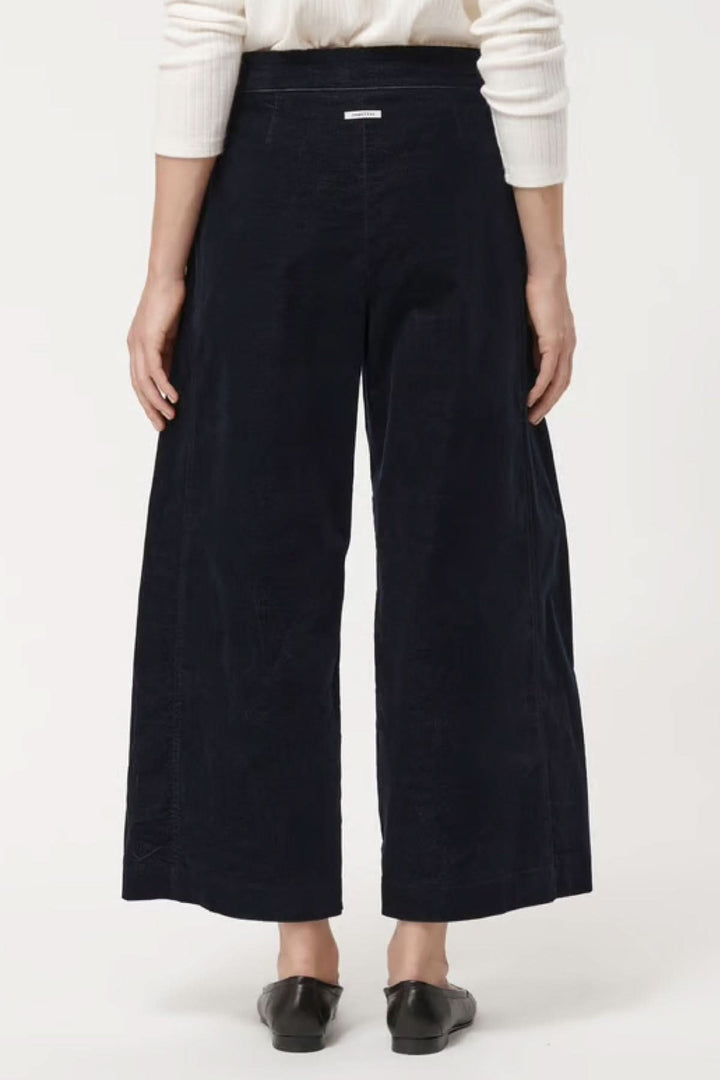 Pantalon en velours côtelé noir ample et raccourci, dos d'une femme, parfait pour l'automne et hiver, style et confort élégants.