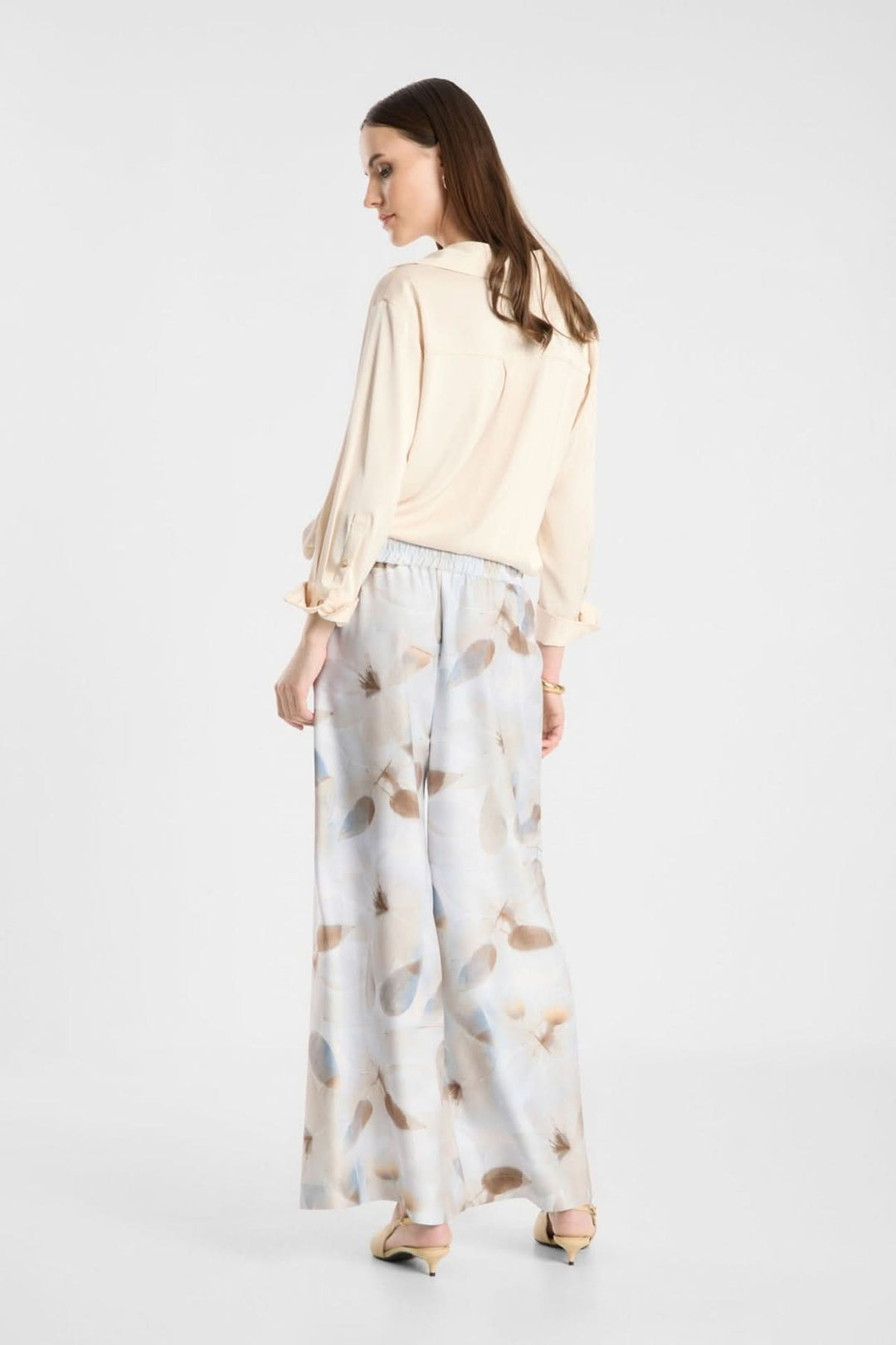 Femme portant un pantalon fluide imprimé à taille élastique, coupe large, tissu léger, look chic et décontracté.