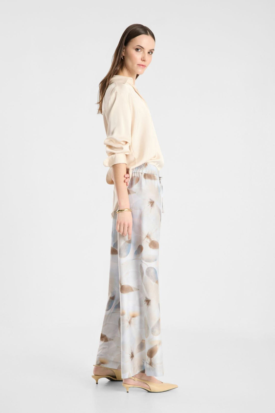 Femme portant un pantalon fluide imprimé à taille élastique avec coupe large et poches discrètes, style chic et décontracté.