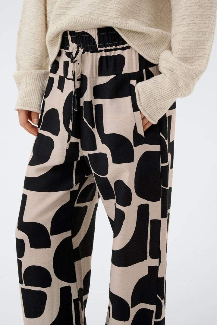 Pantalon fluide motif abstrait Lynn avec coupe ample, taille élastique et motif graphique noir sur beige.