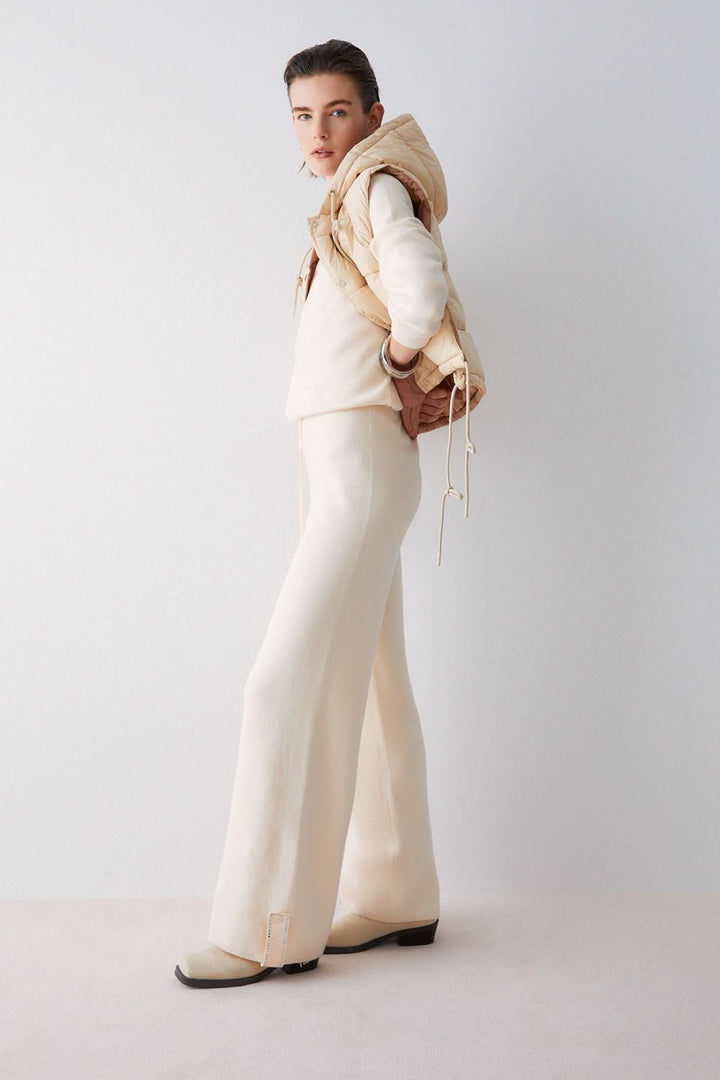 Modèle portant un pantalon jogging en maille à jambe large avec pull et gilet beige.