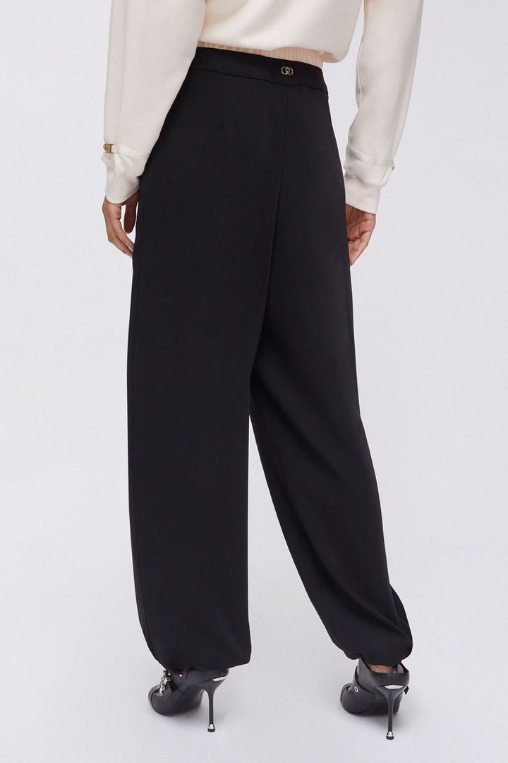 Vue arrière du pantalon large à plis avec taille contrastante noire, montrant la coupe fluide et élégante.