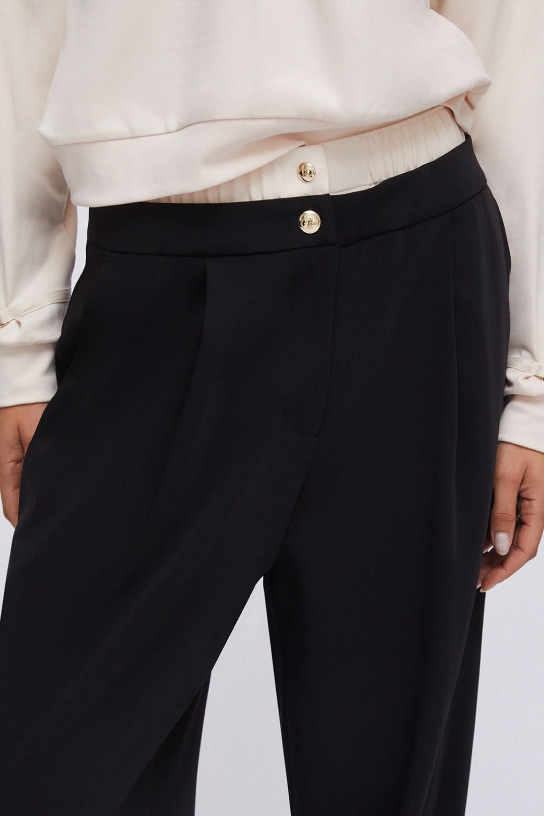 Pantalon large à plis avec taille contrastante et boutons décoratifs, offrant une allure moderne et confortable.