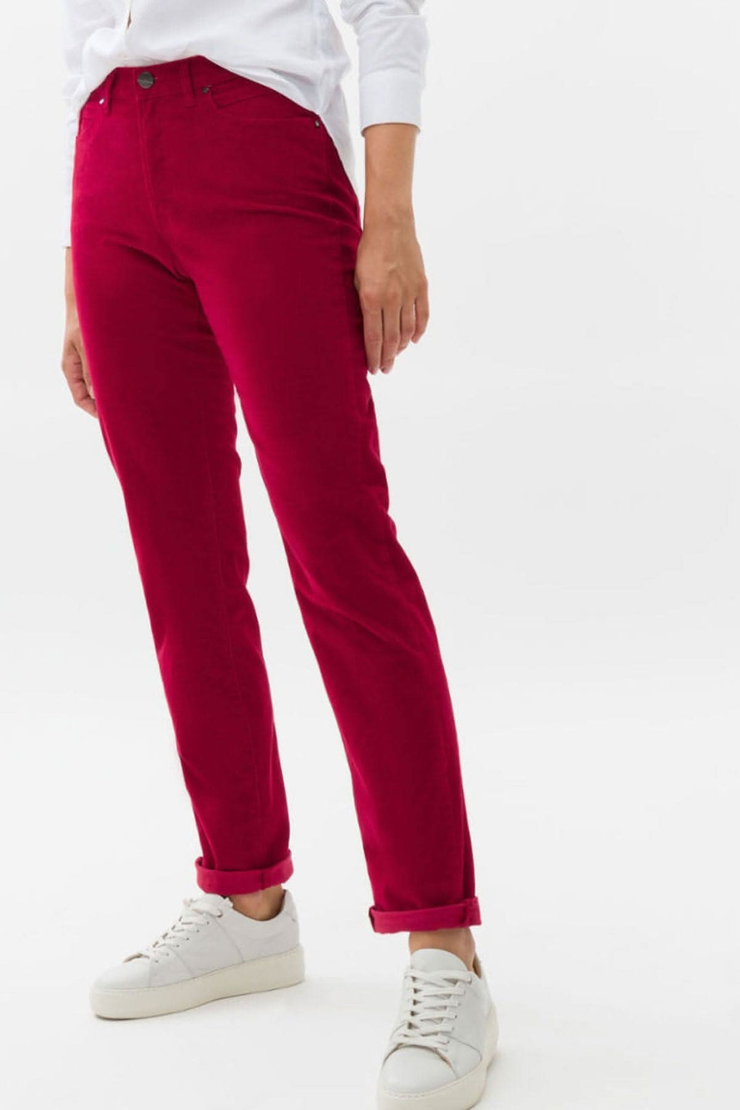 Pantalon velouté Mary en fuchsia, coupe classique à cinq poches, porté avec des chaussures blanches.