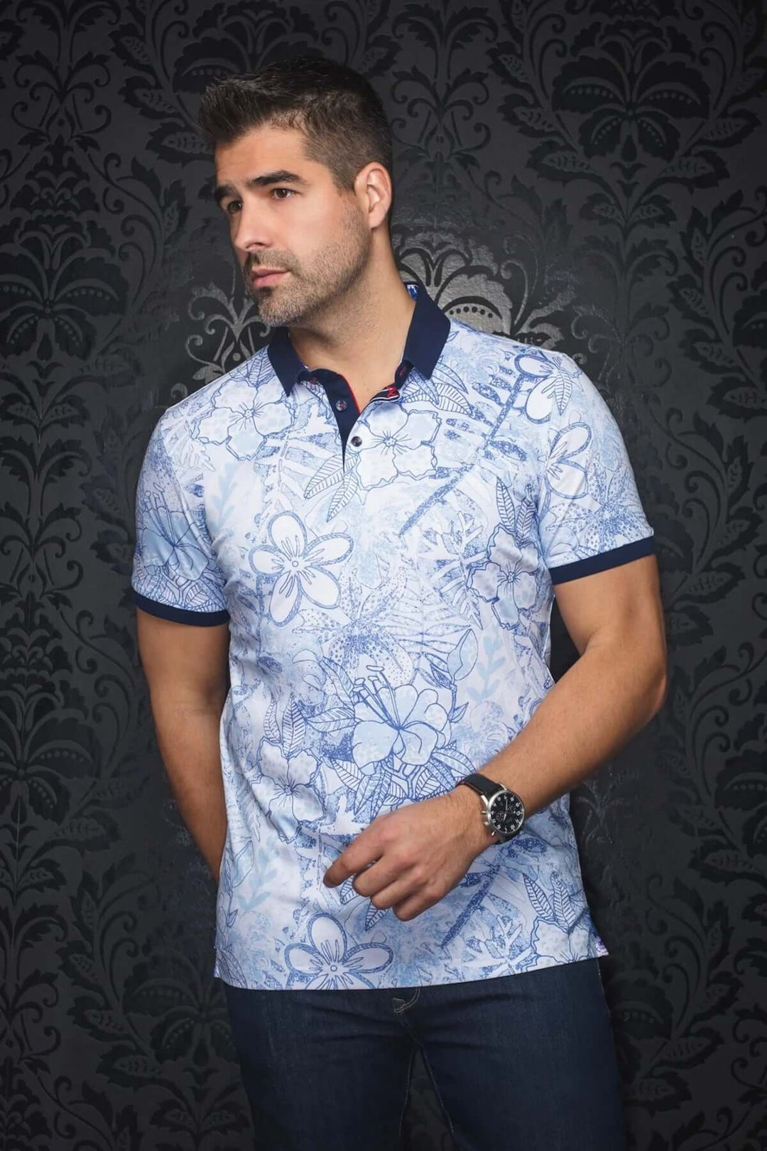 Homme portant un polo bleu à motifs floraux, col contrastant et détails raffinés, style décontracté et habillé.