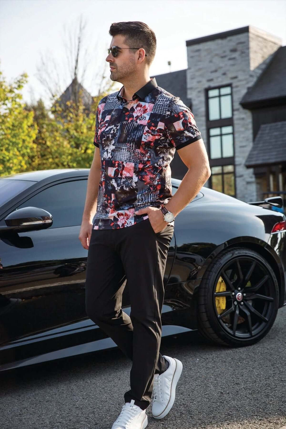 Homme en polo coloré, détails sophistiqués, devant une voiture noire, style décontracté et élégant.