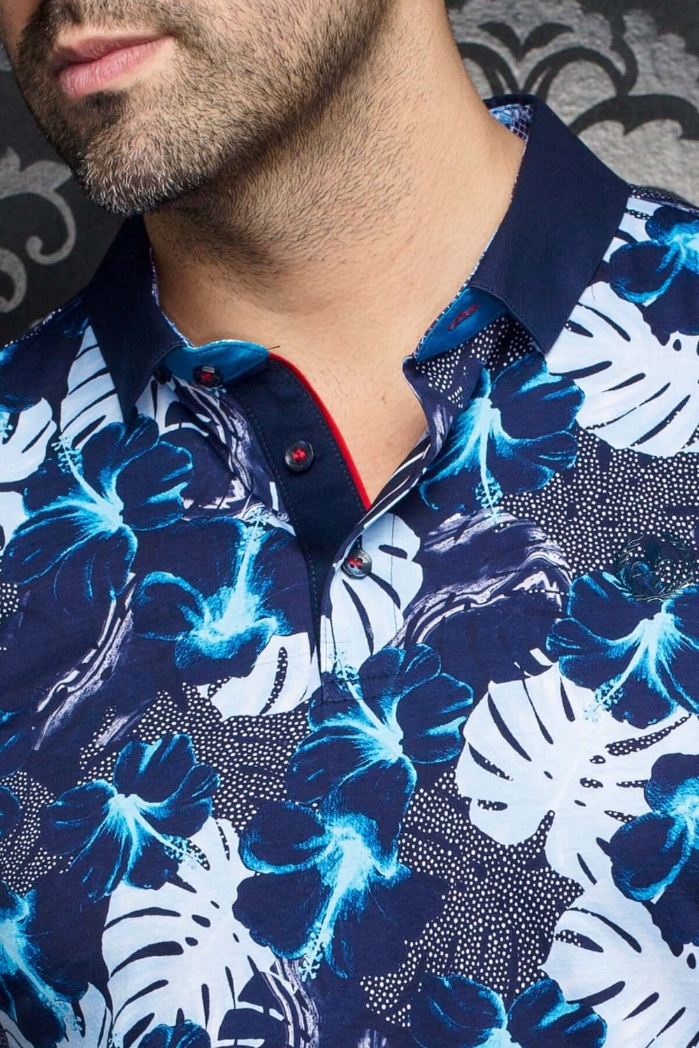 Polo Campari à motifs tropicaux bleutés avec col contrastant bleue marine et détails en rouge.