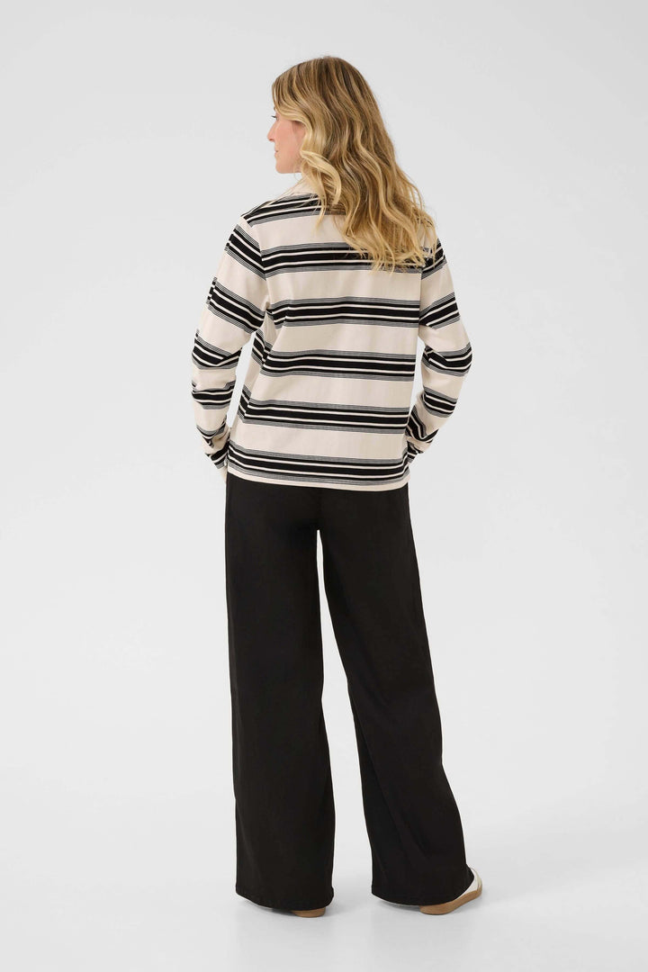 Femme portant le Polo Carmell à rayures élégantes, vue de dos, style casual chic.