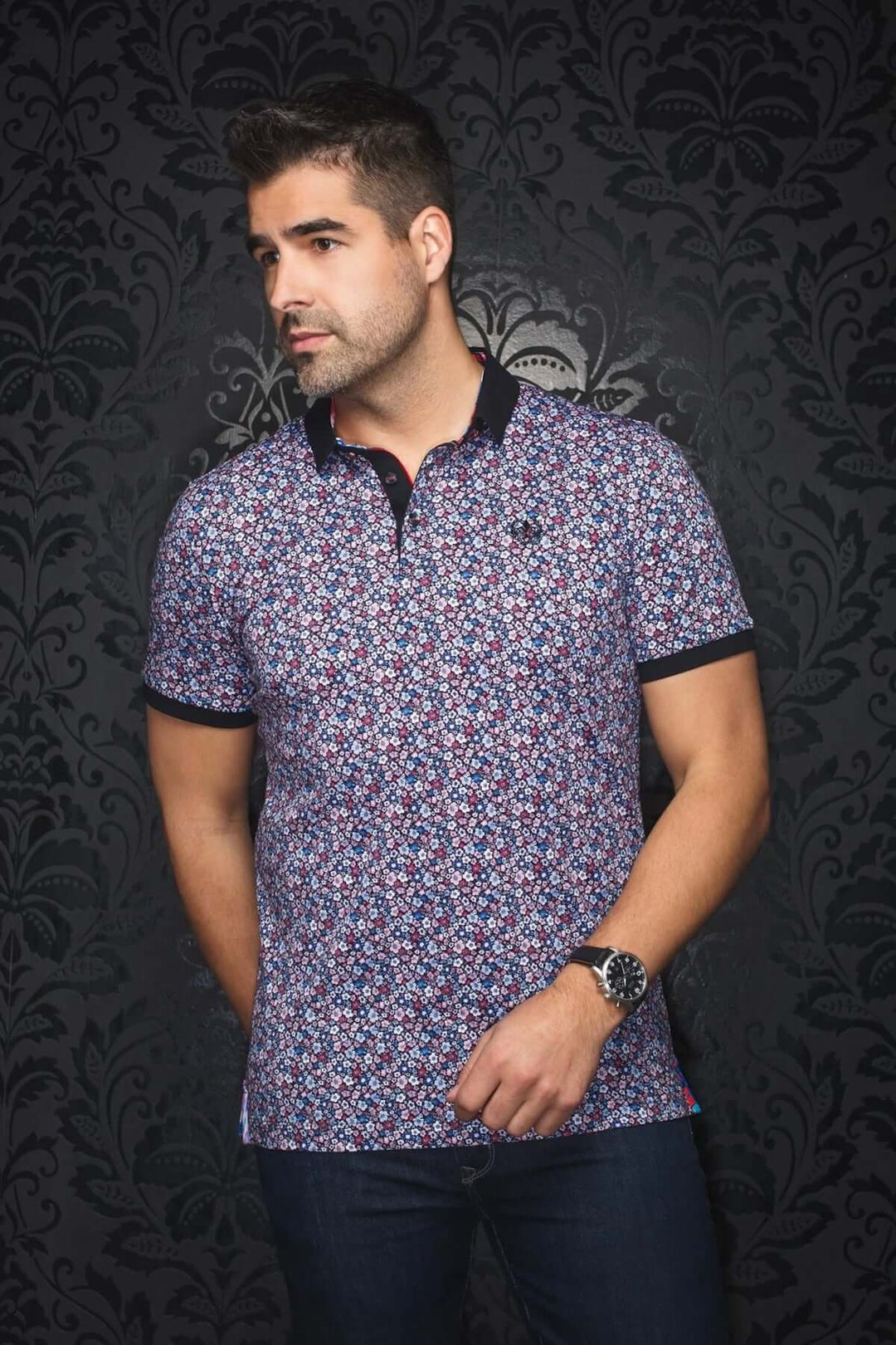 Polo floral moderne avec col noir, motif coloré, style estival pour hommes, porté avec un pantalon uni.