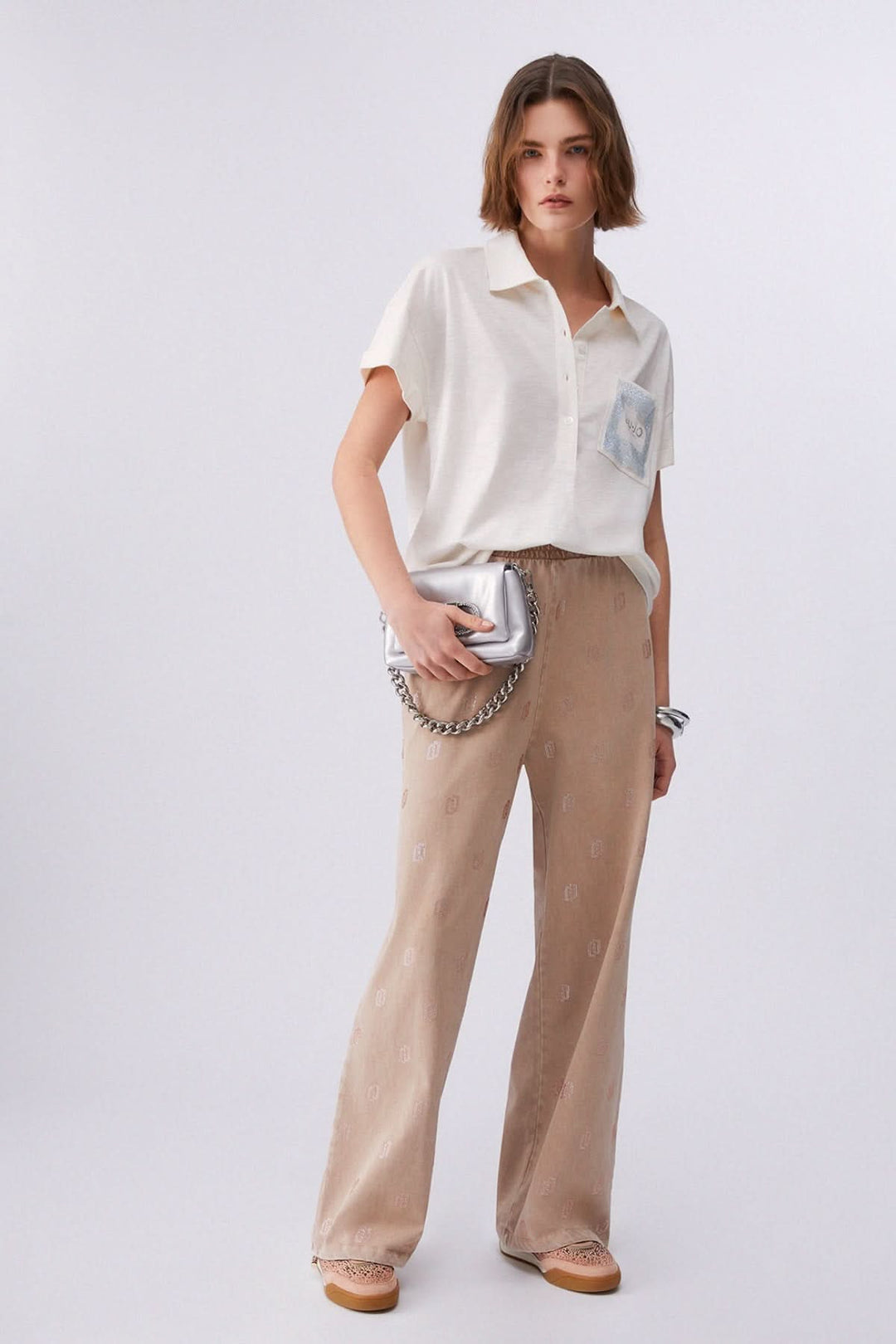 Femme portant un polo à manches courtes avec poche décorative et pantalon beige.