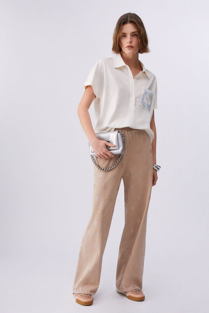 Femme portant un polo à manches courtes avec poche décorative et pantalon beige.