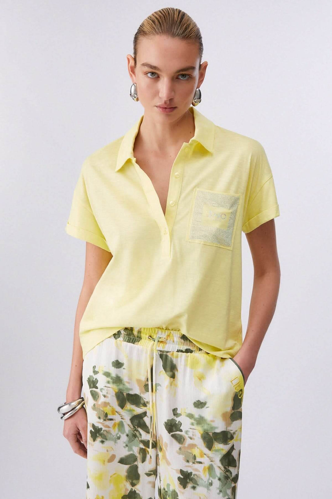 Femme portant un Polo à manches courtes avec poche décorative jaune, style décontracté, avec pantalon imprimé floral.