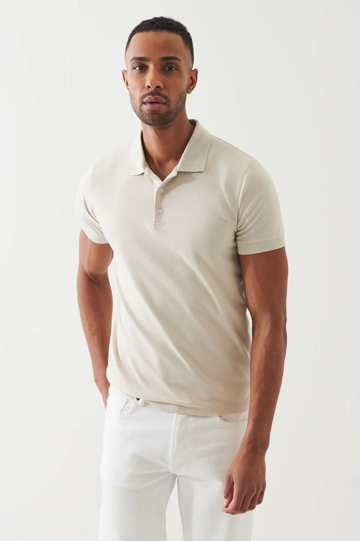 Homme portant un polo épuré beige à manches courtes, avec une coupe ajustée et un col classique.