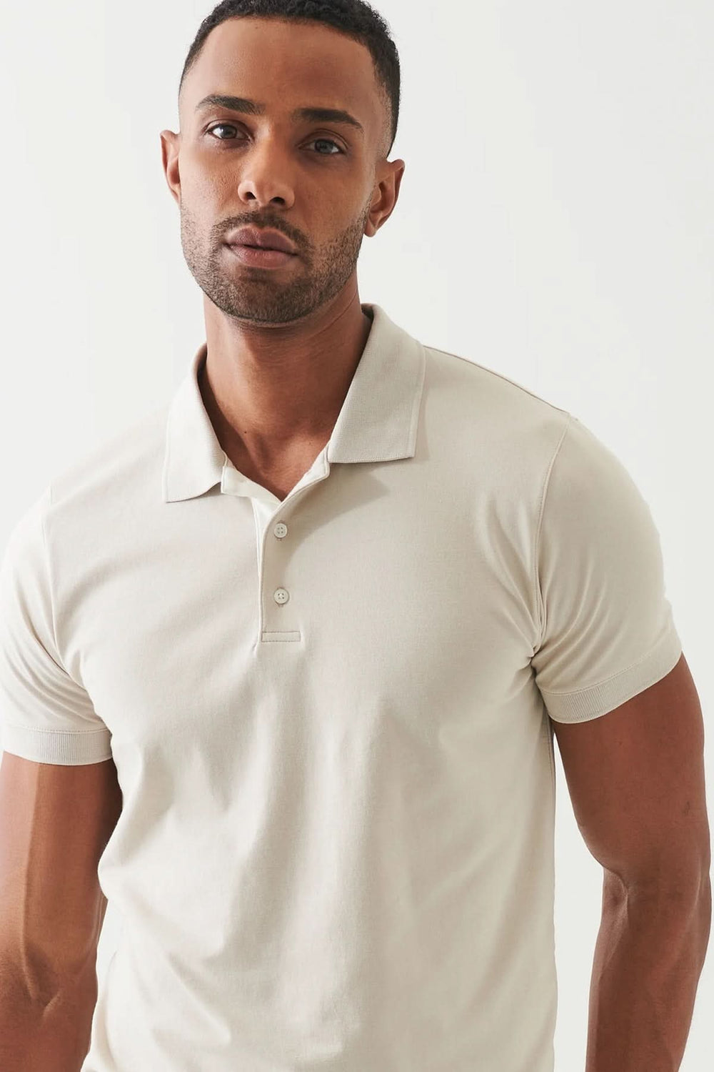 Polo épuré à manches courtes, coupe ajustée, couleur beige, parfait pour un style décontracté soigné.