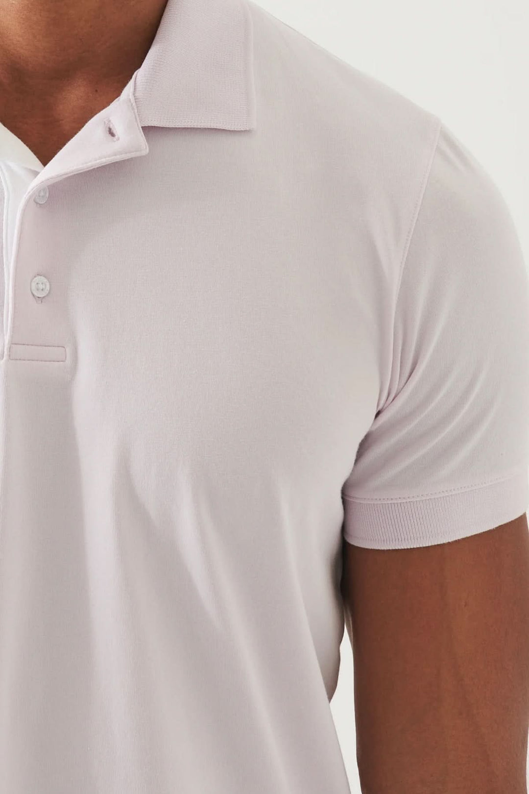 Polo épuré à manches courtes, coupe ajustée, couleur rose clair, col classique et patte de boutonnage discrète.