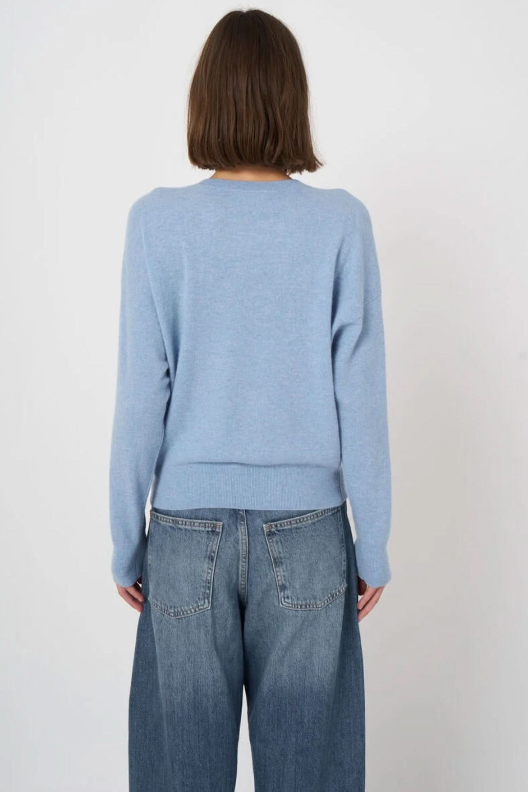 Pull à col rond bleu en tricot fin, vue de dos, coupe droite et manches longues, porté avec un jean décontracté.