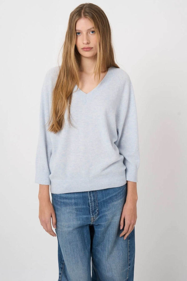 Modèle portant un pull en tricot à col en V, silhouette fluide, confortable, idéal pour un look décontracté ou soigné.