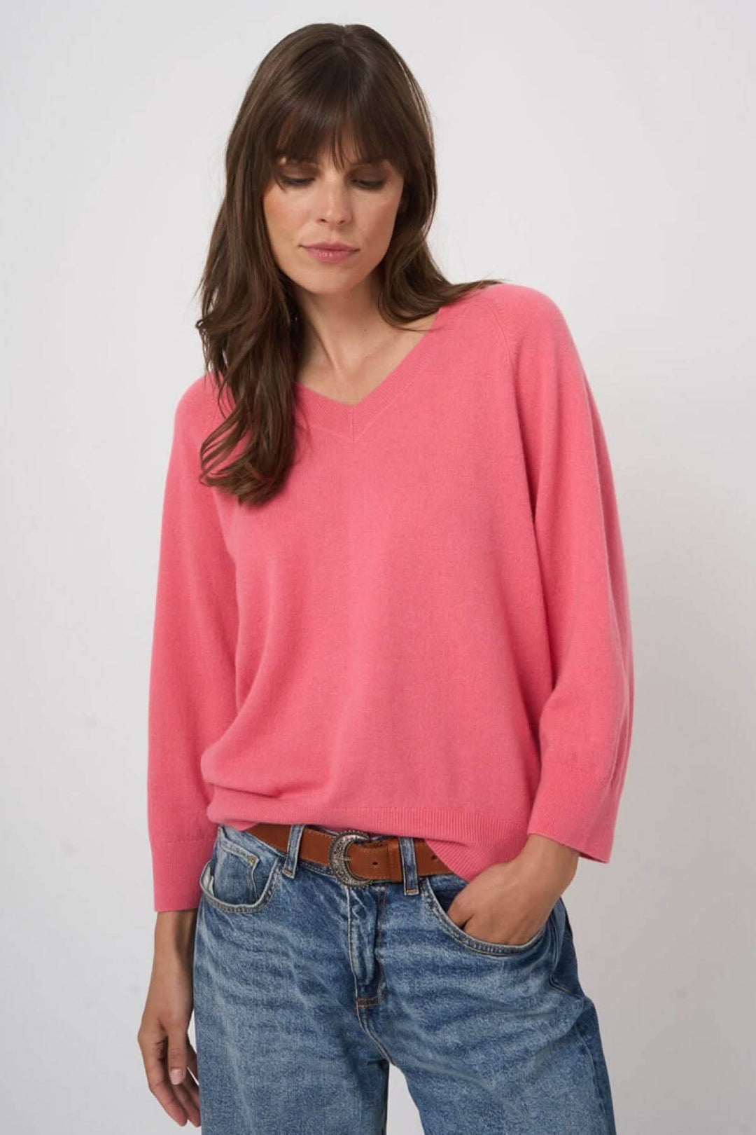 Modèle portant un pull en tricot à col en V rose, coupe droite et manches longues, style élégant et décontracté.