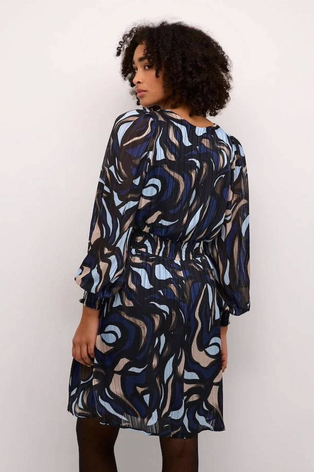 Robe Margo à col en V, bleue, noire et beige, avec manches longues et silhouette fluide.