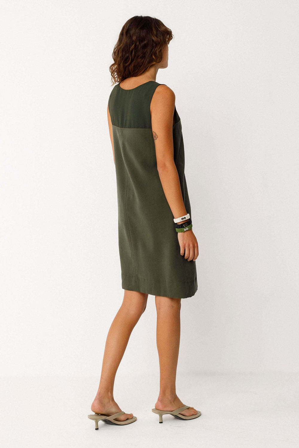 Robe Adara courte fluide sans manches col rond, vue de dos montrant la silhouette élégante et minimaliste du modèle en kaki.
