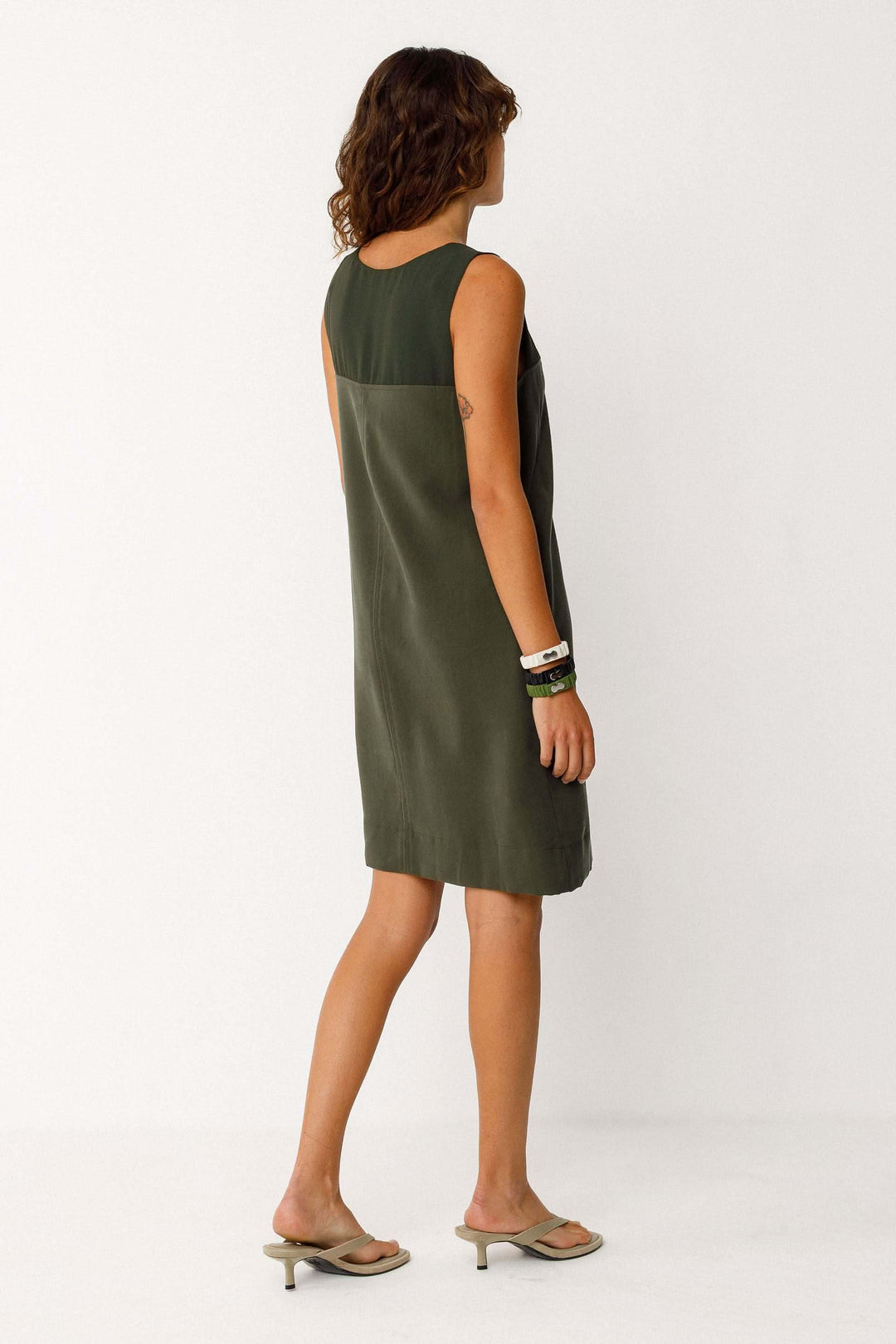 Robe Adara courte fluide sans manches col rond, vue de dos montrant la silhouette élégante et minimaliste du modèle en kaki.
